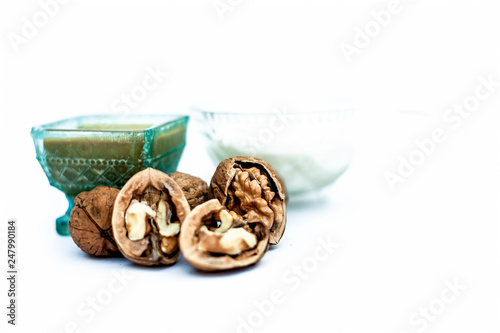 Close up of walnut face pack to prevent hair damage isolated on white i.e. walnut powder well mixed with curd in a glass bowl with entire raw ingredients. photo