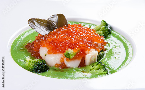 Cream of broccoli soup with scallops and red caviar, on white background