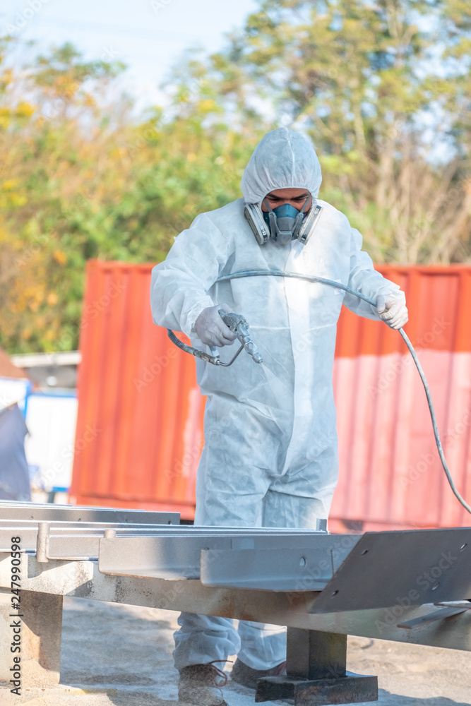 worker painting a mechanical part with airless spray worker painting a mechanical part with airless spray
