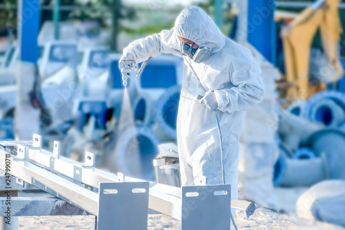 worker painting a mechanical part with airless spray