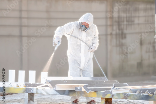 worker painting a mechanical part with airless spray