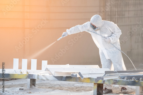 worker painting a mechanical part with airless spray