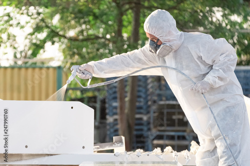 worker painting a mechanical part with airless spray