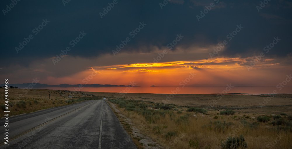 Sunset on the Antelope Island on the great Salt Lake outside the City, colorful orange dusk above a road with buffalos panorama background