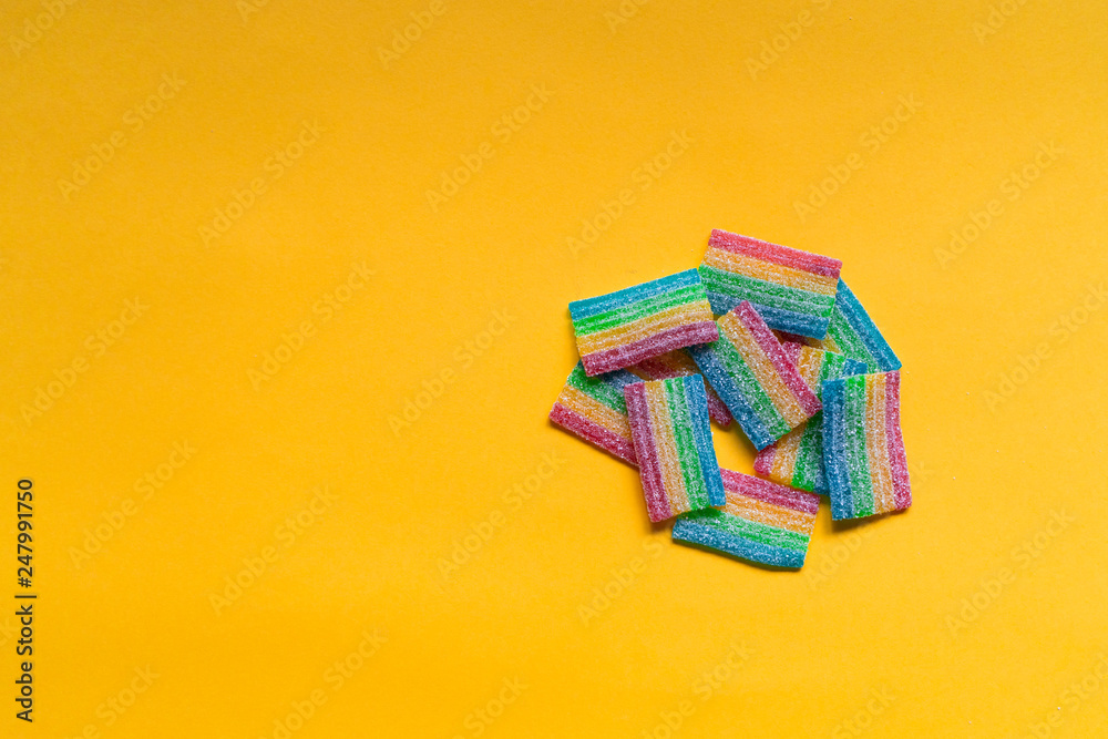 Rainbow chewy sour candies isolated on yellow background. Rainbow chewy sour candies isolated on yellow background.