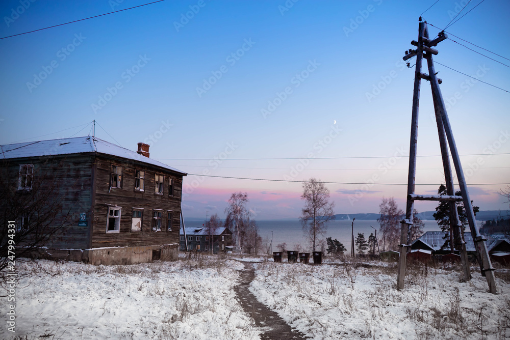 old wood frame house in the snow at sunset