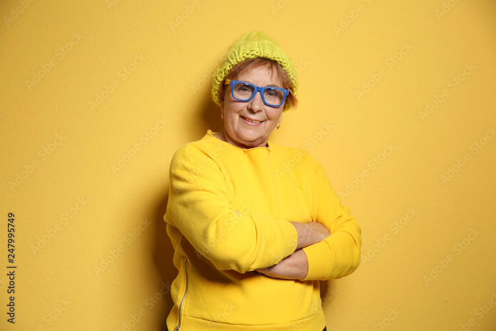 Portrait of elderly woman in hipster outfit on color background