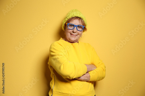 Portrait of elderly woman in hipster outfit on color background © New Africa