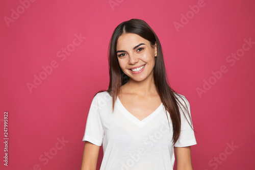 Portrait of young woman laughing on color background