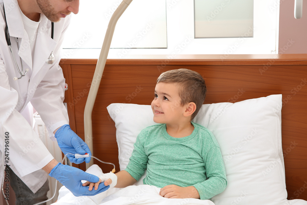 Fototapeta premium Doctor adjusting intravenous drip for little child in hospital