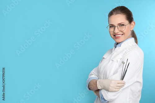 Billede på lærred Female dentist holding professional tools on color background