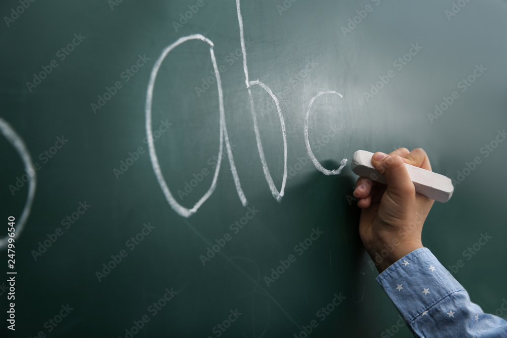 Little child writing letters on chalkboard, closeup