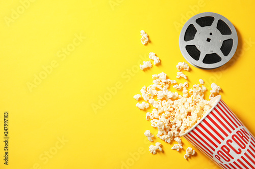 Flat lay composition with popcorn, reel and space for text on color background. Cinema snack