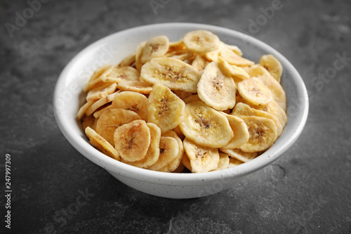 Bowl with sweet banana slices on grey background. Dried fruit as healthy snack