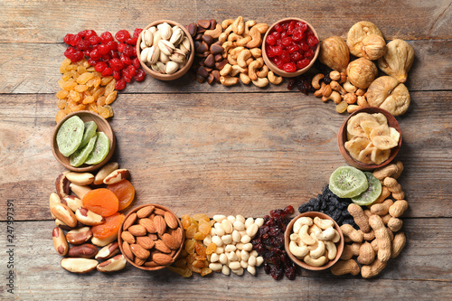 Frame of different dried fruits and nuts on wooden background, top view. Space for text