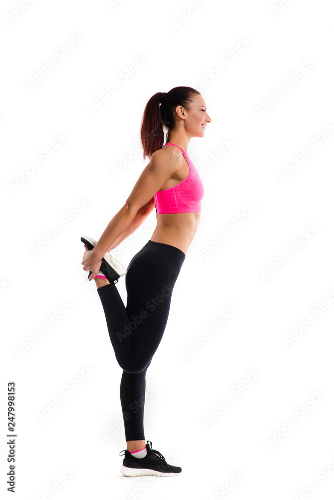 Young fitness woman doing stretching her legs. Photo of muscular woman in fashionable sportswear on white background. Strength and motivation. Young fitness woman doing stretching her legs. Photo of muscular woman in fashionable sportswear on white background. Strength and motivation.