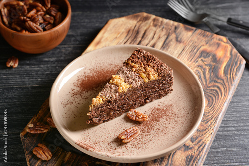Plate with piece of tasty chocolate cake with pecan nuts on table