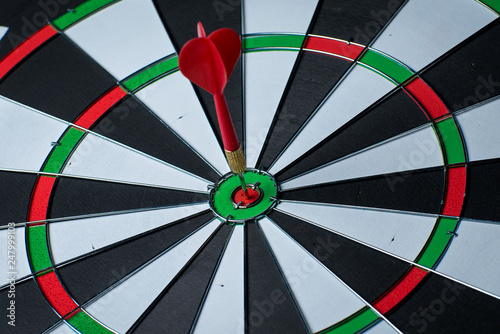 Close up shot red dart arrow on center of dartboard, metaphor to target success, winner concept, Isolated on white background with clipping path 