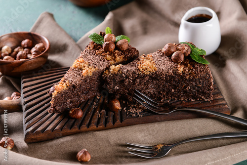 Wooden board with pieces of tasty chocolate cake on table photo