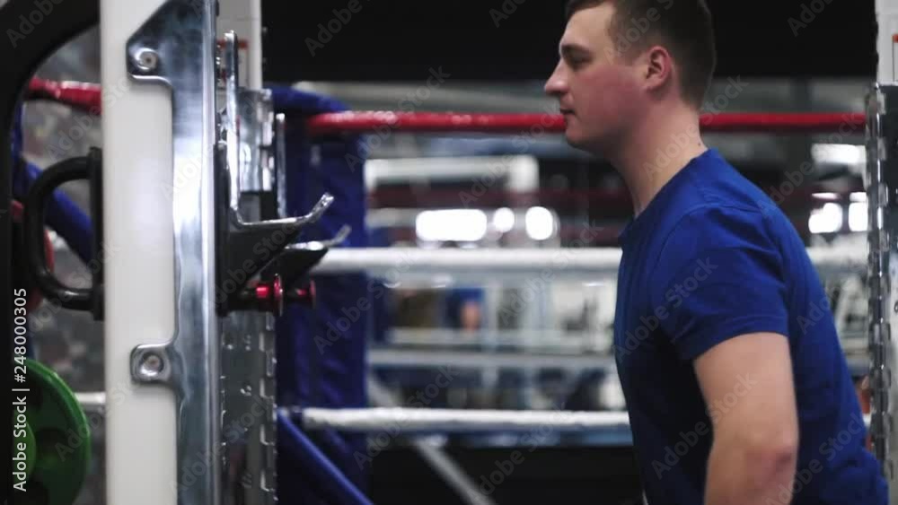 Male is trying to adjust olympic bar before squats workout in the gym Shallow depth of field.