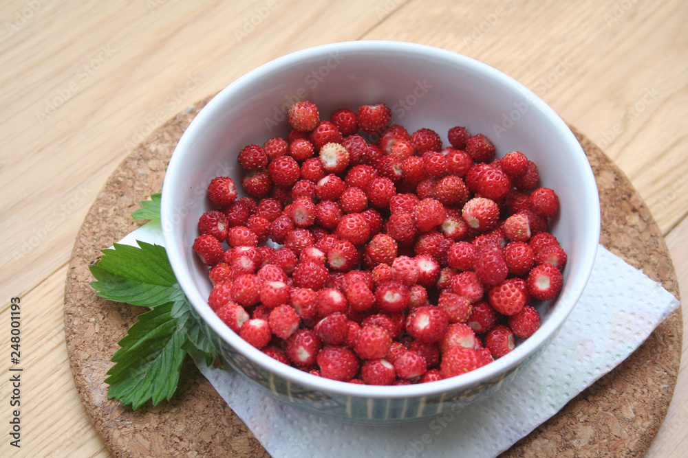 Fresh wild strawberries in a bowl on wooden table Fresh wild strawberries in a bowl on wooden table
