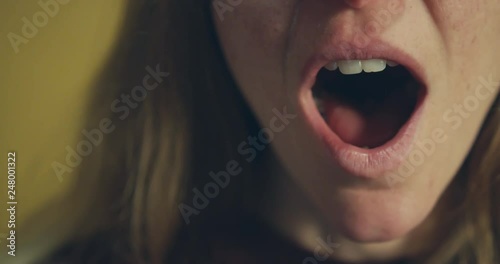 Close up of young woman yawning