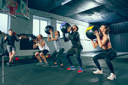Functional fitness workout at the gym with medicine ball. The group of young people during training session. Fit athletic men and women at health club. Healthy lifestyle concept © master1305