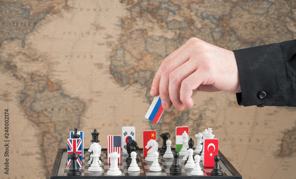 Politician's hand moves a chess piece with a flag. Conceptual photo of a political game. retaliatory move of Russia