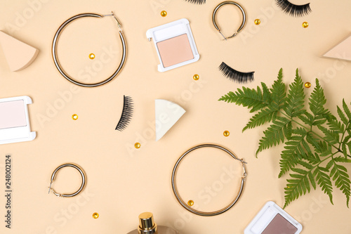 Makeup cosmetics with golden earrings and sponges on color background © Pixel-Shot