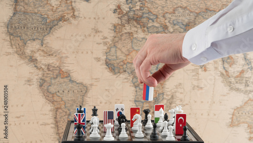 Politician's hand moves a chess piece with a flag. Conceptual photo of a political game. retaliatory move of Russia photo