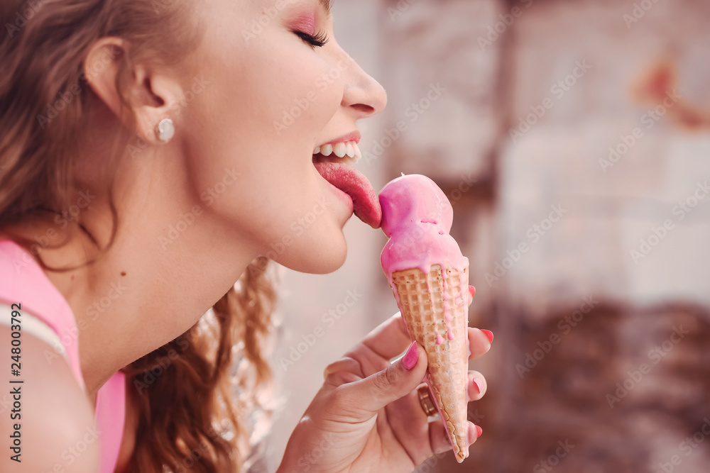 close-up portrait of a young beautiful sexy girl with curly hair in a pink  dress holding a waffle ice cream horn licks and puffs smiling lifestyle  Stock Photo | Adobe Stock