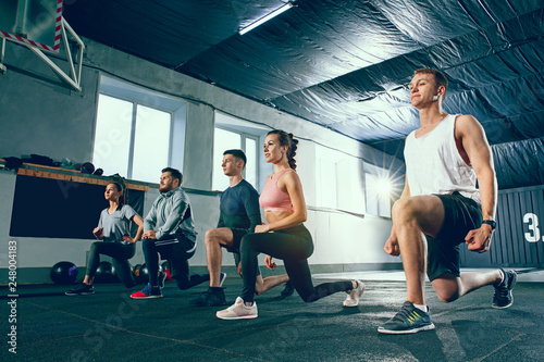 Shot of young men and women at the gym. Functional fitness workout. The group of people during training session. Fit athletic models. Healthy lifestyle concept