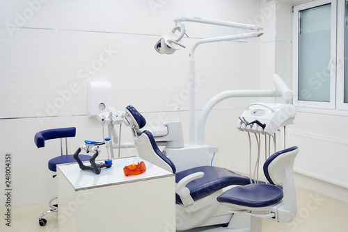New dental chair with white and blue furniture. Dentist’s office