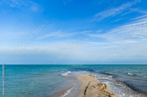 Scenic view of the waves of the blue sea on the sandy shore. Wild nature.