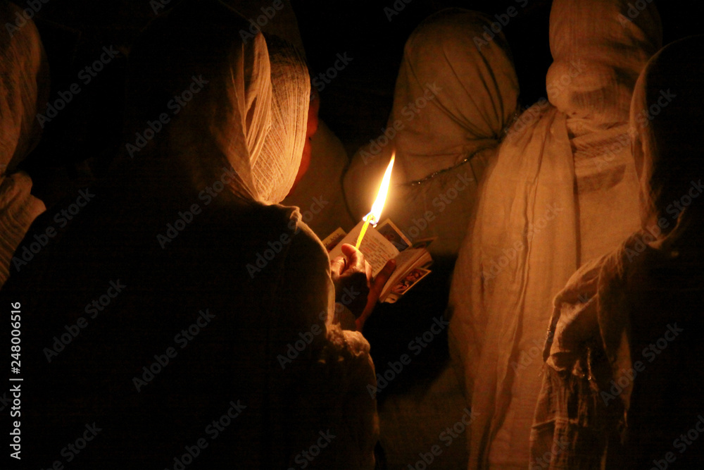 kobieta w chuście modląca się przy świetle świecy w święto trzech króli w etiopii - obrazy, fototapety, plakaty 