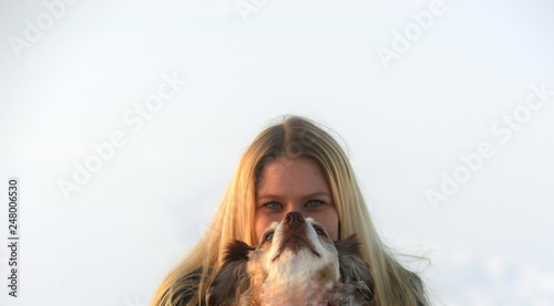 Zwei. Junge langhaarige Frau versteckt sich hinter einem Hund photo