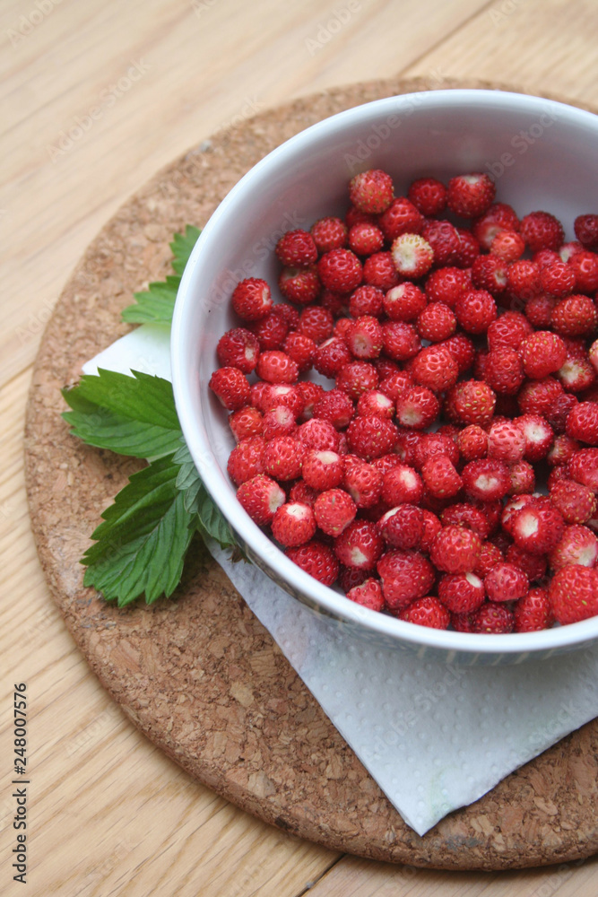 Fresh wild strawberries in a bowl on wooden table Fresh wild strawberries in a bowl on wooden table