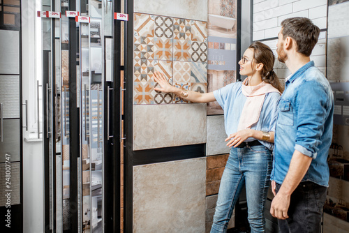Beautiful young couple choosing ceramic tiles for their house repairment in the building shop