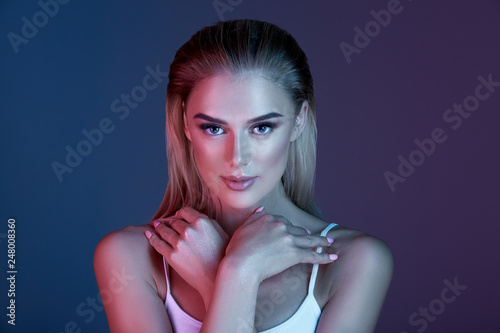 Pretty girl with make up and blonde hair posing with at dark blue background