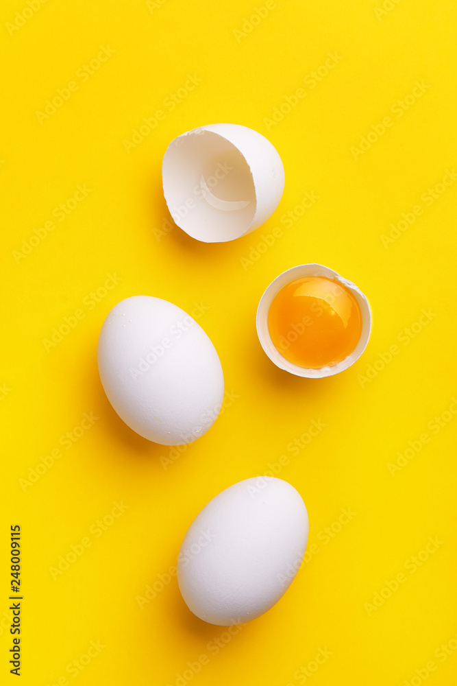 White eggs pattern (broken and whole) on a yellow background viewed from above. Top view