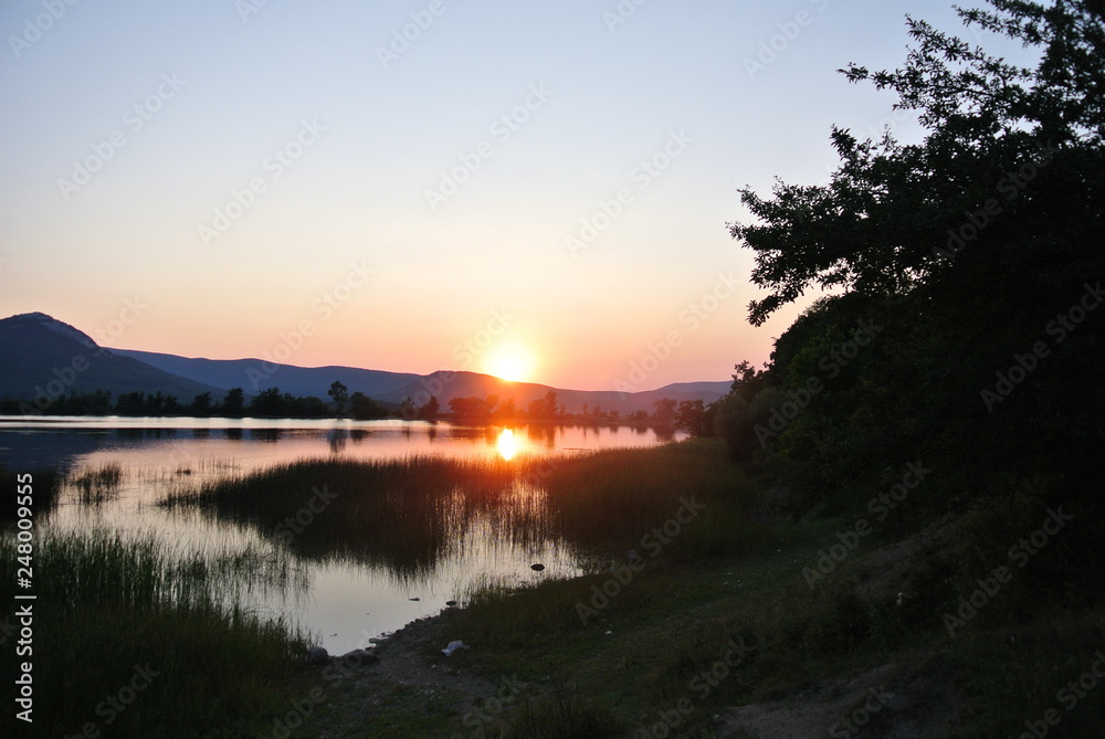Beautiful sunset on the lake in summer with mountain views