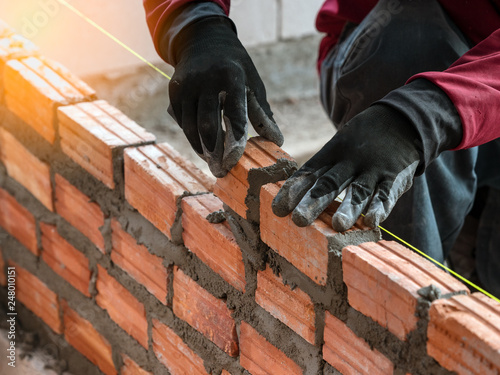 Construction worker installing bricks wall in construction site