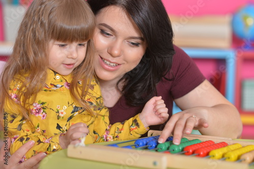 Portrait of mother teaching daughter to use abacus