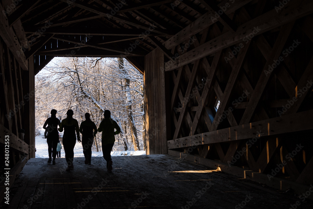 Runners crossing a wooden covered bridge