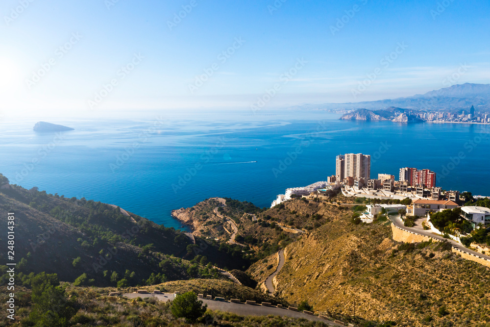 Top view of Benidorm Spain with skyscrapers and mountain roads and the island of Isla on a sunny day