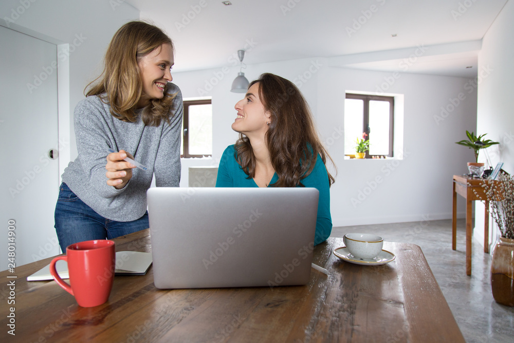 Cheerful female friends watching and discussing media content Cheerful female friends watching and discussing media content