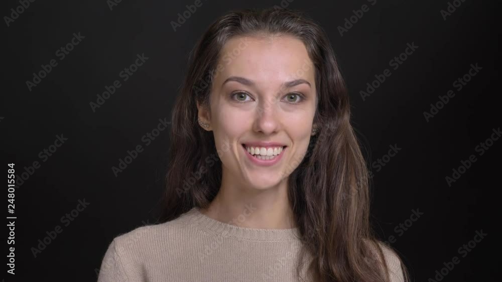 Close-up portrait of brunette long-haired caucasian girl watching smilingly into camera on black background. Close-up portrait of brunette long-haired caucasian girl watching smilingly into camera on black background.