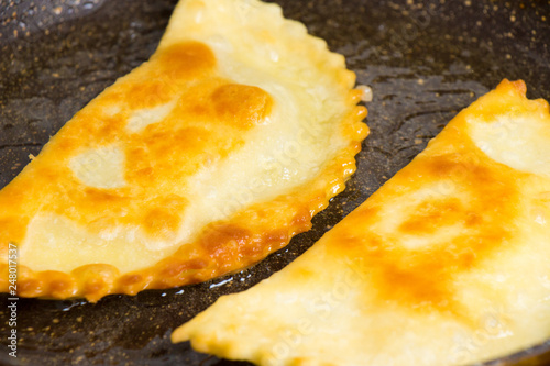 Chebureks are roasted on a hot skillet ruddy crispy tasty photo