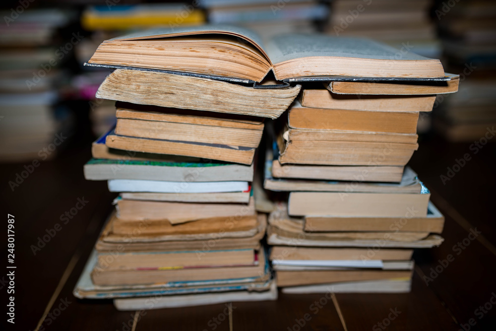 Opened book on columns of books, shallow depth of field, cracked wood floor. Opened book on columns of books, shallow depth of field, cracked wood floor.