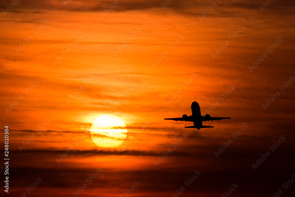 Airplane silhouette in the sunset with red sky and big sun